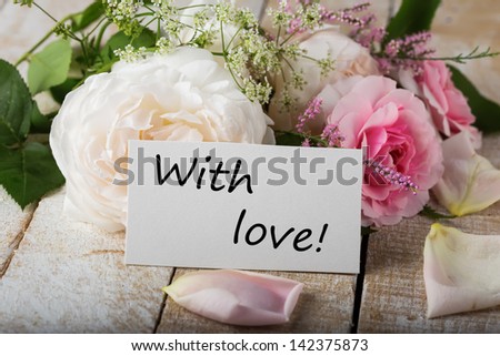 Postcard with fresh flowers and tag with words With love