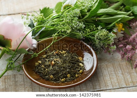 Dry herbal tea on plate on wooden background. Fresh melissa, mint, camomile. Selective focus.