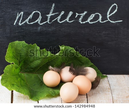 Fresh organic eggs on wooden table. Selective focus. Natural/bio/organic/eco products.Word natural on blackboard.