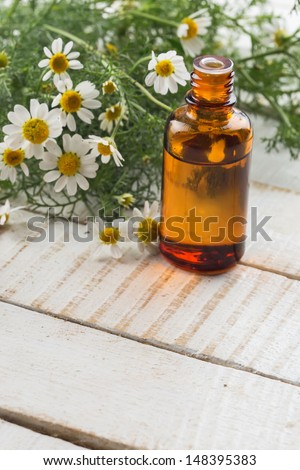 Essential aroma oil with chamomile on wooden background. Selective focus.