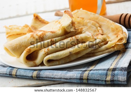 Appetizing pancakes on plate with honey/syrup on white table. Healthy breakfast. Selective focus.