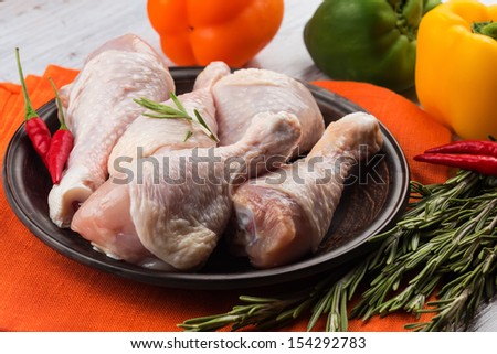 Fresh chicken meat on wooden plate  on white table with vegetables. Selective focus. Rustic style.