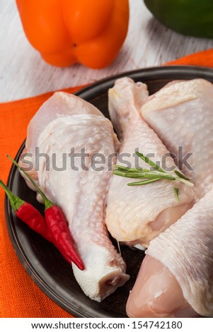 Fresh chicken meat on plate  on white table with vegetables. Selective focus. Rustic style.