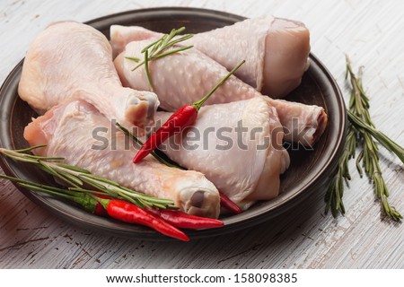 Fresh chicken meat on plate on white table with herbs. Selective focus. Rustic style.