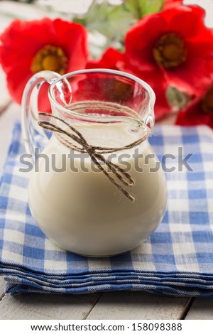 Fresh dairy products - milk in pitcher on wooden table. Rustic style. Bio/organic/natural ingredients. Healthy eating.