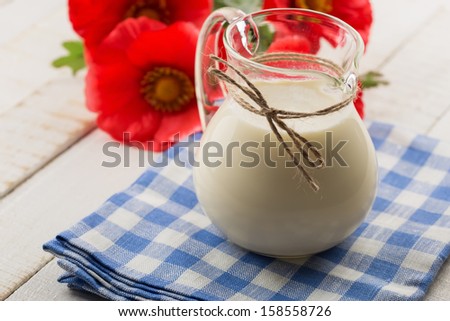 Milk in pitcher on white wooden table. Selective focus. Rustic style.