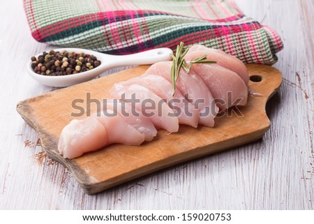 Fresh chicken meat on wooden board on white table with spices. Selective focus.