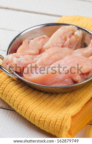Fresh chicken meat in bowl on white background. Selective focus. Rustic style.