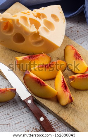Cheese and fruit on wooden board on table. Selective focus.