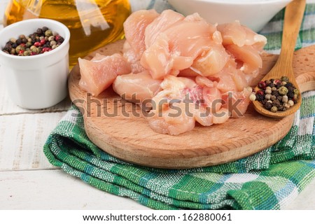 Fresh chicken meat on wooden board on white table with spices. Selective focus. Rustic style.