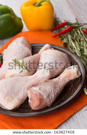 Fresh chicken meat on plate on white table with vegetables. Selective focus. Rustic style.
