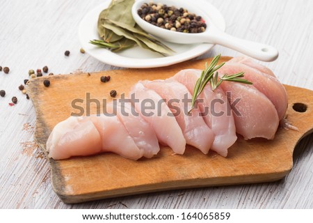 Fresh chicken meat on wooden board on white table. Selective focus. Rustic style.