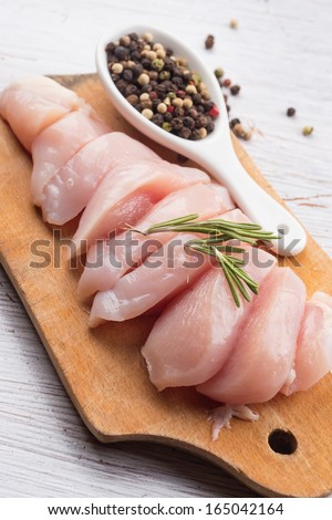 Fresh chicken meat on wooden board on white table. Selective focus. Rustic style.