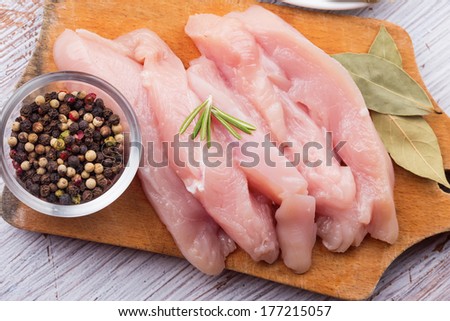 Fresh chicken meat on wooden board on white table with spices. Selective focus. Rustic style.