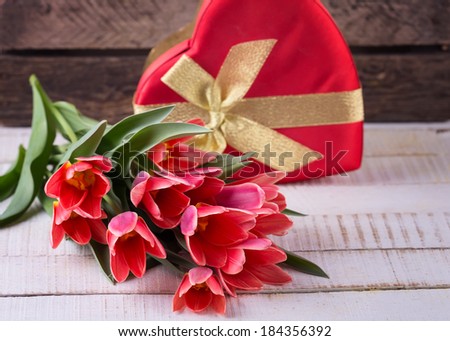Postcard with fresh tulip flowers and gift box on wooden background. Selective focus. Spring, easter background.