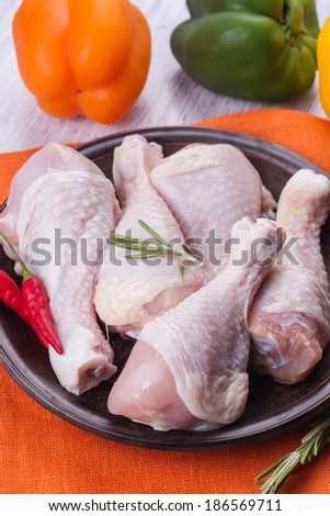 Fresh chicken meat on plate  on white table with vegetables. Selective focus. Rustic style.