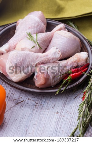 Fresh chicken meat on plate on white table with vegetables. Selective focus, vertical. Rustic style.