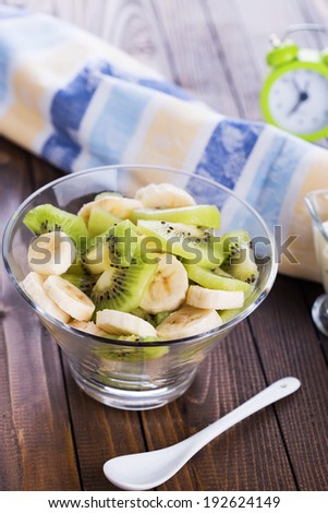 Healthy breakfast. Fresh fruit salad in bowl on wooden background. Selective focus, vertical.