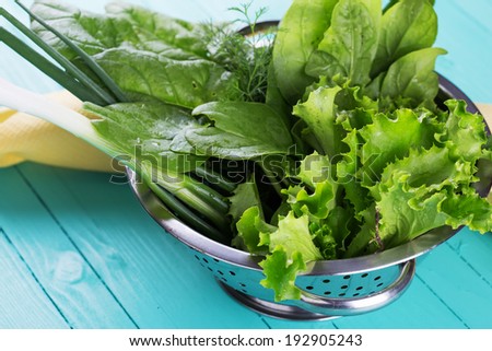 Fresh spinach, salad, onion, fennel, salad in metal bowl on wooden table. Selective focus, horizontal.