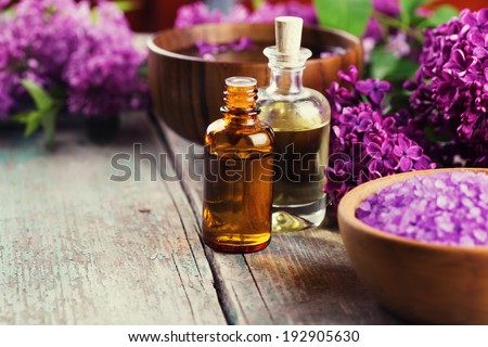 Spa setting on old wooden background. Aroma oil, water with aroma oil, sea salt, flowers. Selective focus, horizontal.
