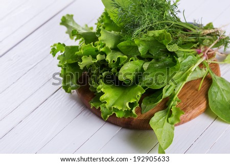 Fresh spinach, salad, onion, fennel, salad on board on wooden table. Selective focus, horizontal.