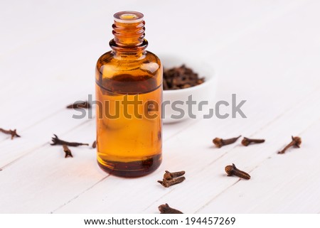Essential aroma oil with cloves on wooden background. Selective focus.