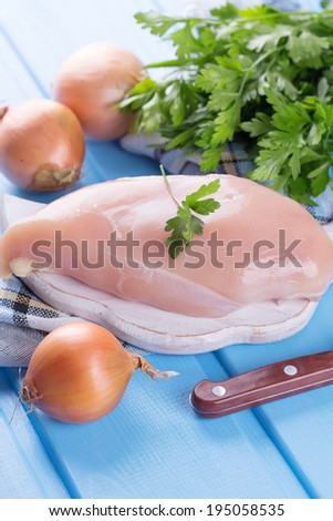 Fresh chicken meat on wooden board on table. Selective focus, vertical.