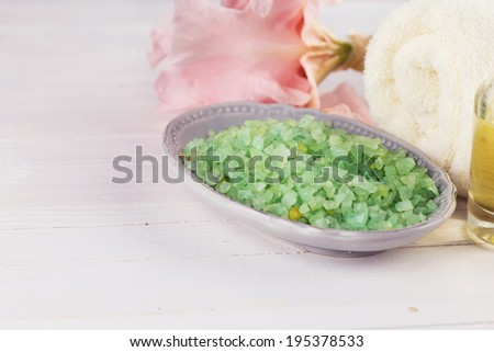 Spa setting on old wooden background. Sea salt, aroma oil, towel, flowers. Selective focus, horizontal.