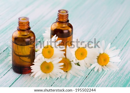 Essential aroma oil with chamomile on wooden background. Selective focus, horizontal.
