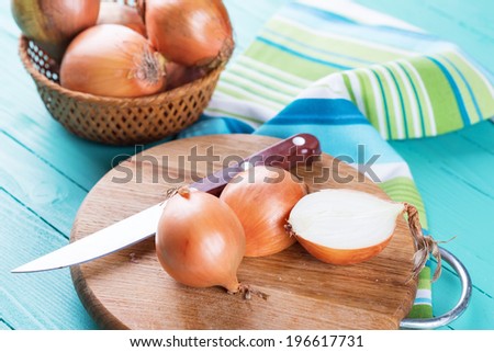 Organic onion on board on wooden background. Selective focus, horizontal.