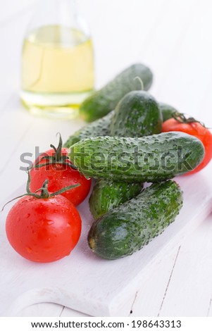 Fresh organic cucumbers and tomatoes on white wooden table. Selective focus. Natural/organic/bio/healthy products.