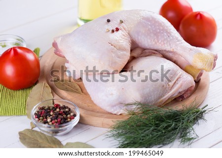 Fresh chicken meat on wooden board on white table with vegetables. Selective focus. Rustic style.