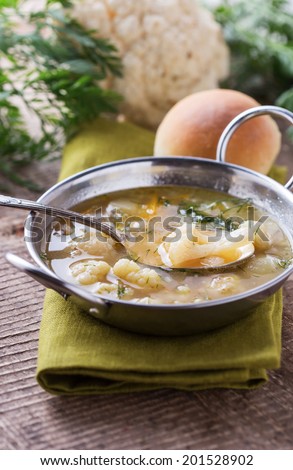 Soup with vegetables cauliflower, potato, onion in bowl on wooden background. Selective focus, vertical.