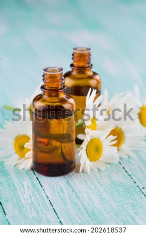 Essential aroma oil with chamomile on wooden background. Selective focus, vertical.