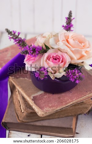 Fresh summer flowers and old books on wooden table. Vintage background.