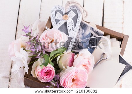 Box with flowers and old photos  on wooden background. Selective focus.