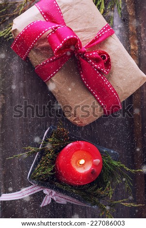 Decorative christmas composition from gift box and candle  on aged wooden background. Selective focus.