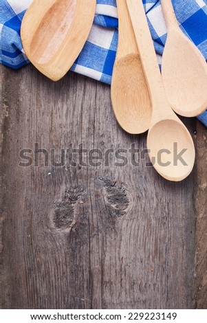 Bright kitchen towel  and wooden spoons on aged wooden background.
