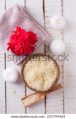 Spa setting with sea salt, flower, towel and candles on white painted wooden boards. Selective focus.