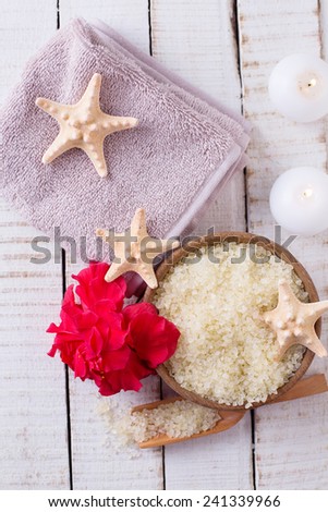 Spa setting with sea salt, flower, towel and candles on white painted wooden boards. Selective focus.