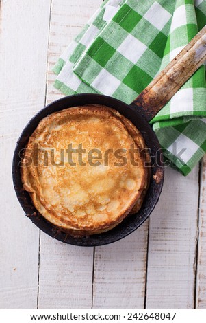 Pancakes on pan on white wooden background. Selective focus.