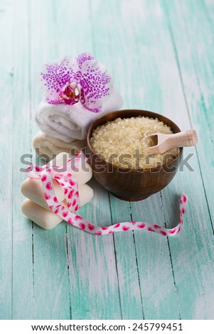 Spa setting with sea salt, soap, towel and flower on aqua painted wooden boards. Selective focus.