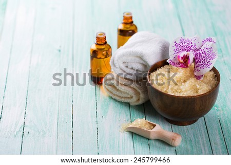 Spa setting with sea salt, soap, towel and flower on aqua painted wooden boards. Selective focus is on flower.