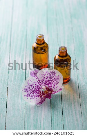 Extract of orchid flowers in bottle on aqua wooden background. Selective focus.