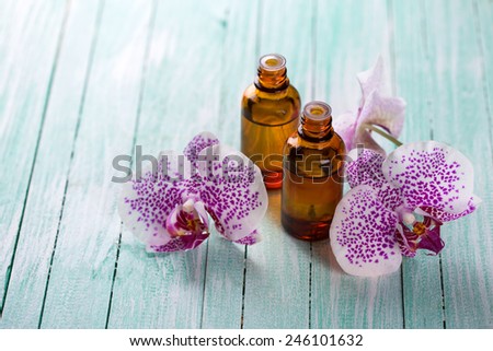 Extract of orchid flowers in bottle on aqua wooden background. Selective focus.