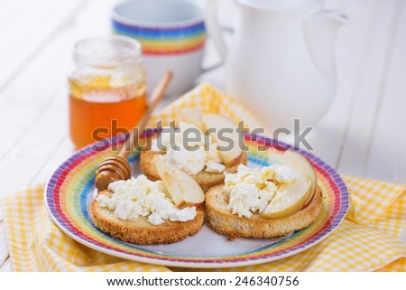 Bread with cottage cheese or ricotta, honey and apple on plate on wooden background. Selective focus. Healthy eating.