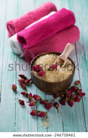 Spa setting with sea salt, soap, towel and flower on aqua painted wooden boards. Selective focus is salt in bowl.
