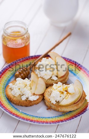 Bread with cottage cheese or ricotta, honey and apple on plate on wooden background. Selective focus. Healthy eating.