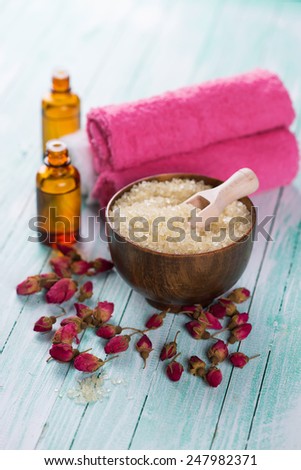 Spa setting with sea salt, soap, towel and flower on aqua painted wooden boards. Selective focus is salt in bowl.