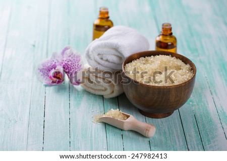 Spa setting with sea salt, soap, towel and flower on aqua painted wooden boards. Selective focus is on salt in bowl.